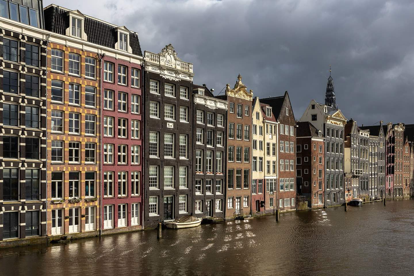 Narrow canal houses along the Damrak at golden hour