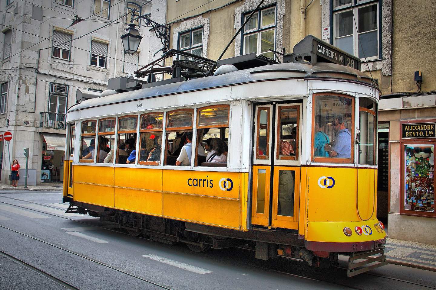 A yellow tram 28 passing through a Lisbon street