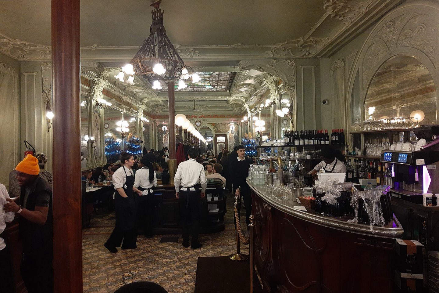 Warmly lit dining room of a Paris bistro with banquettes and mirrors
