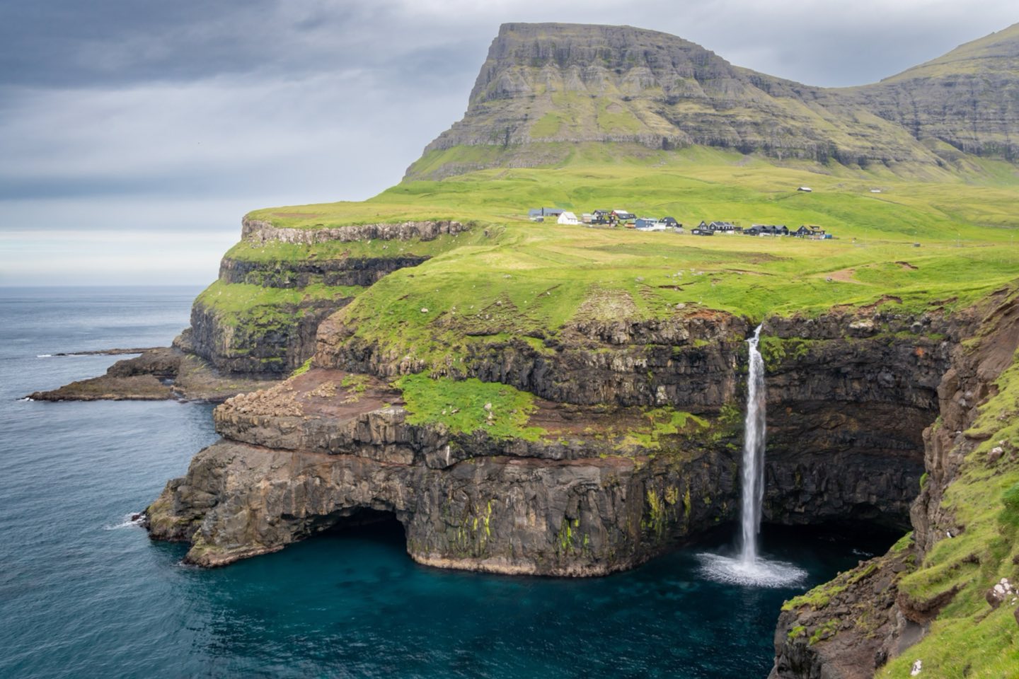 The Múlafossur waterfall dropping off a sea cliff below the village of Gásadalur