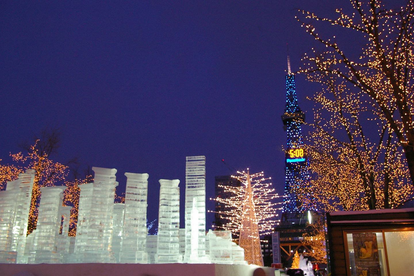 Ice sculptures lit at night in Odori Park, with the Sapporo TV Tower behind