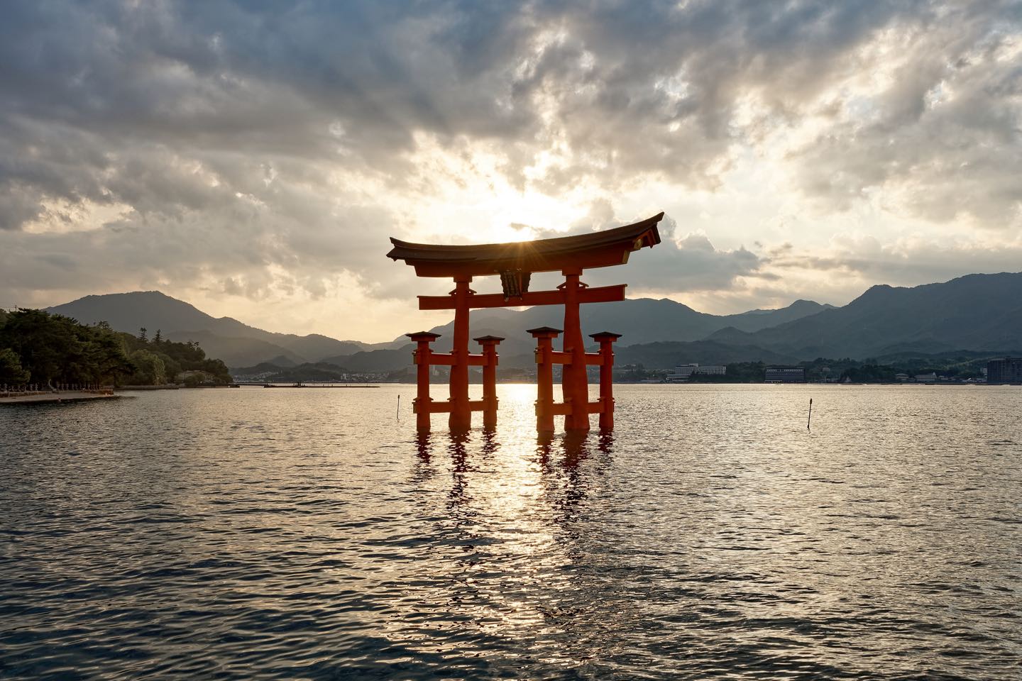 The vermilion torii of Itsukushima Shrine standing in the sea at sunset