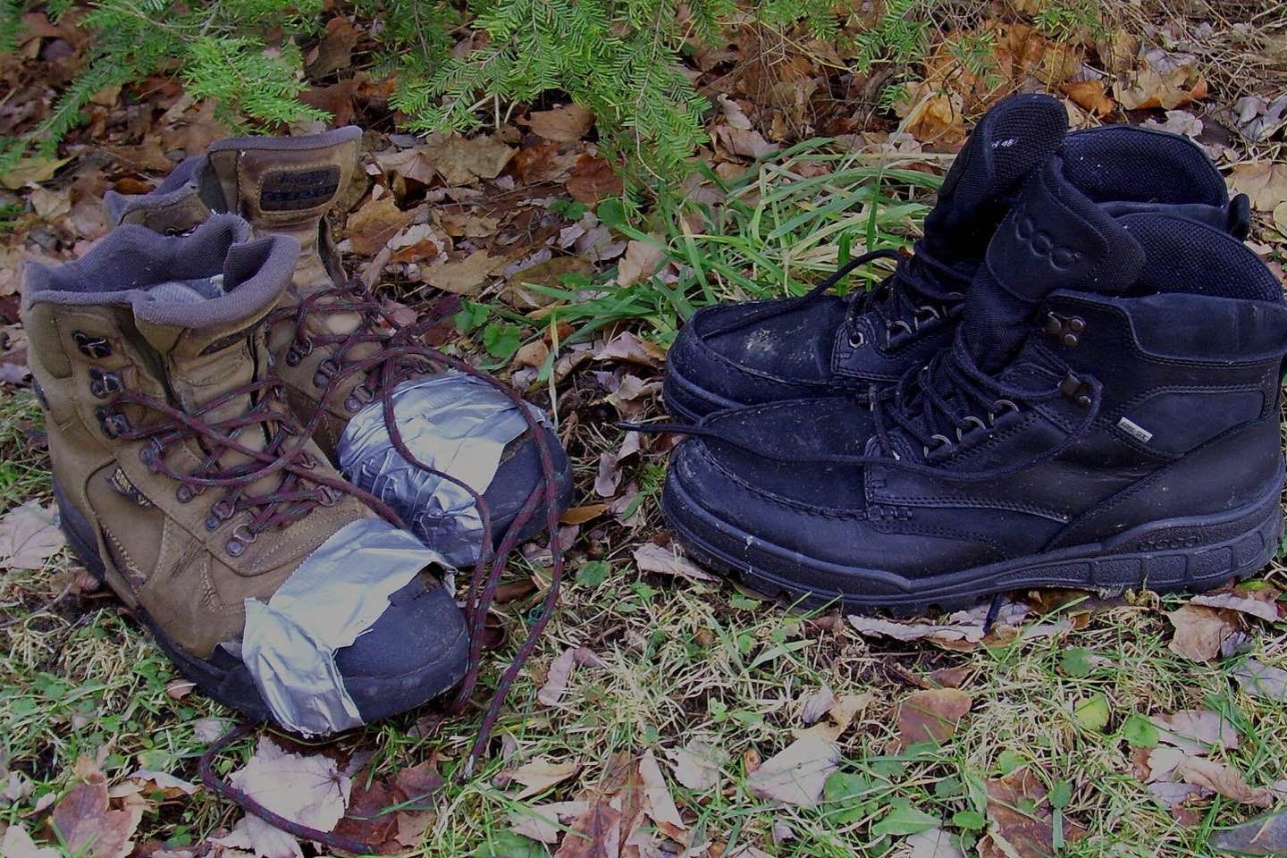 Two pairs of hiking boots, one worn and taped, one new