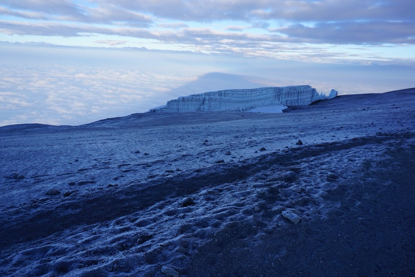 A wall of glacier ice on the summit plateau of Kilimanjaro at dawn above a sea of cloud