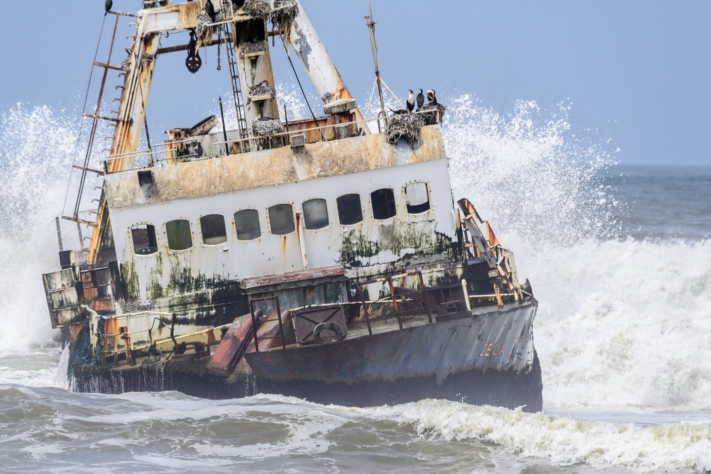 The wreck of the trawler Zeila in the surf of the Skeleton Coast, with cormorants on its mast