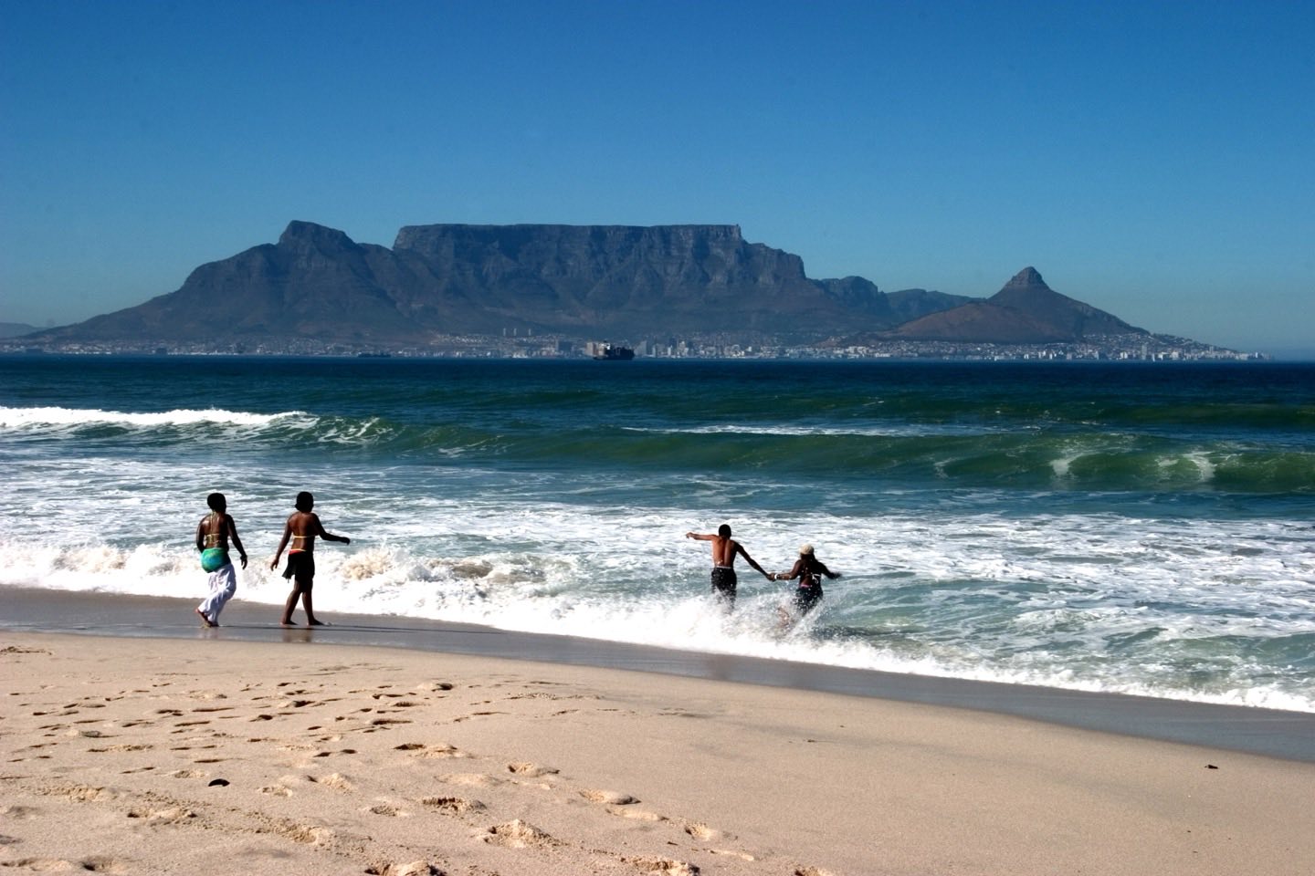 Table Mountain and Lion's Head across Table Bay from the beach at Blouberg, with people in the surf